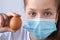 Young girl in a medical mask holds a chicken egg. Close-up portrait