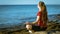 Young girl meditating on the coast in yoga pose