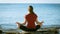 Young girl meditating on the coast in yoga pose