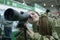 Young girl in military uniform looking through portable monocular telescope, gun shop
