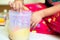 Young girl mixing a solution of oil and lye undergoing saponification in a transparent container for making home made