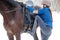 Young girl mounting on her bay horse for riding