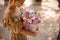 Young girl neatly holds box with composition of different flowers and looks at it.