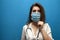 Young girl nurse puts on a viral mask on a blue background, protection of the coronavirus epidemic