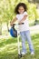 Young girl outdoors on scooter smiling