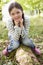 Young girl outdoors in woods sitting on log