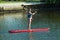 Young Girl Paddle Boarding on Red Board on Water