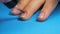 Young girl paints her nails with light pink nail polish On a blue background in home. Make yourself a manicure.