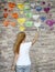 A young girl paints a watercolor rainbow heart on the stone wall