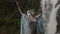 Young girl perfoming meditative dance on a rock close to stream of falling water