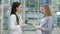 Young girl pharmacist advises pregnant customer. Pharmaceutical store concept