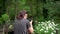 A young girl, a photographer, in a forest area, takes pictures of flowers and beautiful nature.