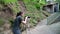 A young girl, a photographer, in a forest area, takes pictures of an old house and beautiful nature.