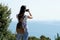 Young girl photographing beautiful unpolluted nature and horizon line on the open sea, with a smartphone