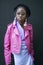 A young girl in a pink jacket and big glasses, with earrings in the form of a doll Barbie posing during the London Fashion Week.