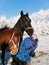 Young girl play with two foals on pasture in winter