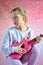 Young girl playing guitar , pink background with stars