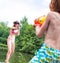 Young girl playing squirt guns with her brother on pier during summer