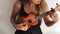 Young girl playing ukulele with white wall backgroung at home. HD.