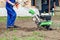 Young girl plows the land with a cultivator in spring garden