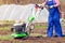 Young girl plows the land with a cultivator in spring garden