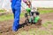 Young girl plows the land with a cultivator in spring garden