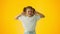 Young girl plugging her ears with her fingers and looking dissatisfied on a yellow background. Concept of lack of