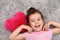 Young girl with plush red heart lying on the carpet