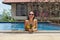 The young girl in the pool with pineapple in hands and a happy smile wearing sunglasses and a yellow bathing suit.