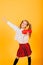 Young girl with portable wireless speaker enjoying and dancing on yellow background