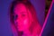 Young girl portrait in neon pink and violet lights with glitter freckles on face. Clubber, night life concept.
