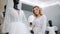 Young girl poses in a bridal shop against the background of bridal gown. Model show new fashion collection of dress