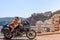 Young girl posing. Motorcycle for tourism and travel. Wearing a helmet. In the background are views of the sea and hotels. Coast