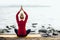 Young girl practices yoga in parvatasana lotus position position on seashore background, rear view. Concept of biohacking