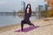 A young girl practices yoga by the river.