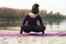 A young girl practices yoga by the river.