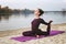 A young girl practices yoga by the river.