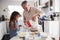 Young girl preparing cake mixture with her grandfather at the kitchen table, close up