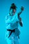 Young girl professional judoist isolated on blue studio background in neon light. Healthy lifestyle, sport concept.