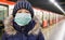 Young girl in protective sterile medical mask on her face looking at camera on tube station,  virus, Chinese pandemic coronavirus