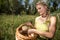 A young girl puts a mushroom - Macrolepiota procera - into a woven basket.