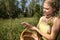 A young girl puts a mushroom - Macrolepiota procera - into a woven basket.