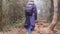 Young girl in raincoat with backpack going on exotic wood trail during travel. Hiking woman walking in tropical wet