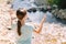 Young girl raises her arms praying on the banks of a mountain stream