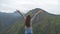 Young girl reaching up top of mountain and raised hands. Woman tourist standing on the edge of beautiful canyon