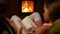 Young girl reading a book sitting in a rocking chair by the fire