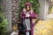 A young girl in a red coat is waiting for a meeting on the street, checking the time