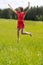 Young girl in a red dress jumping in a field