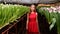 Young girl in a red dress posing in a greenhouse of flowers tulips