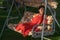 A young girl in a red dress is resting on a country swing